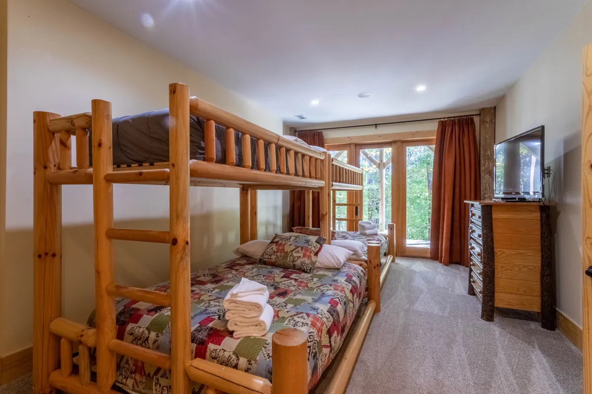 A playful and inviting kids’ bunk room with a bunk bed dressed in colorful bedding, large windows letting in natural light, and ample space for fun and independence. The setting is bright and cheerful, designed for younger guests to enjoy.